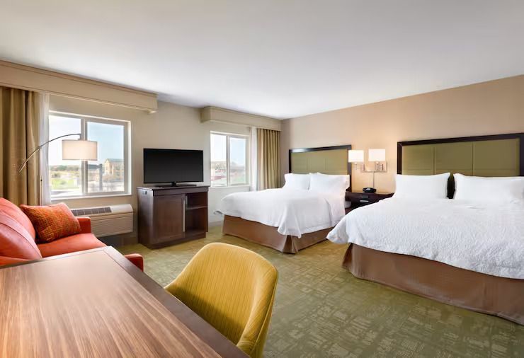 A hotel room with two beds , a couch , a desk and a television.