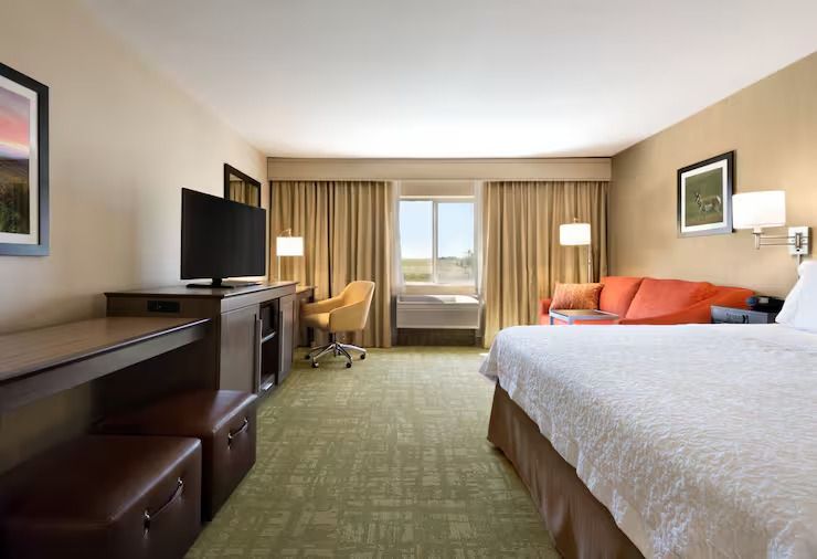 A hotel room with a king size bed , couch , desk and television.