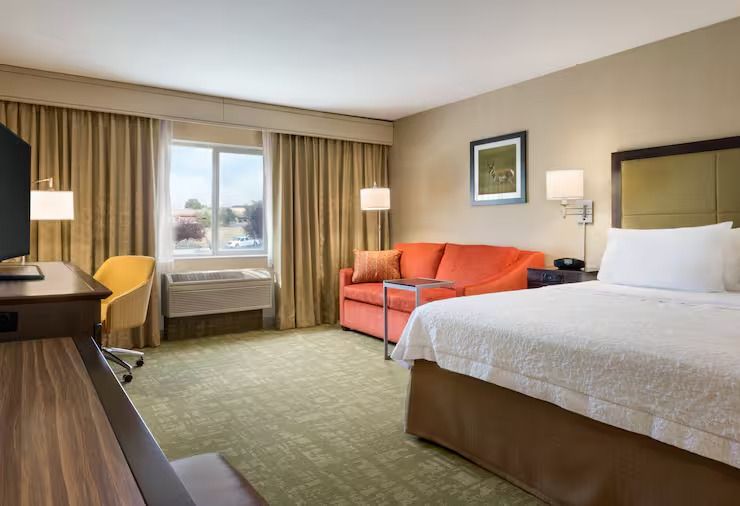 A hotel room with a king size bed , couch , desk and television.