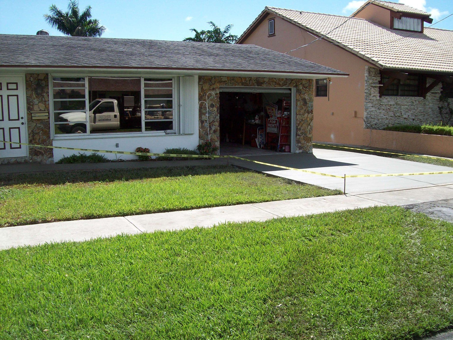 Suburban house with a garage and green lawn; a car is visible inside the garage.