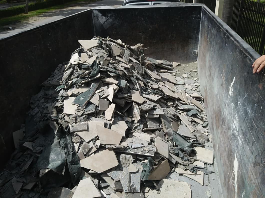 Two people loading a dark cabinet into a truck with a ramp. Boxes are visible in the truck.