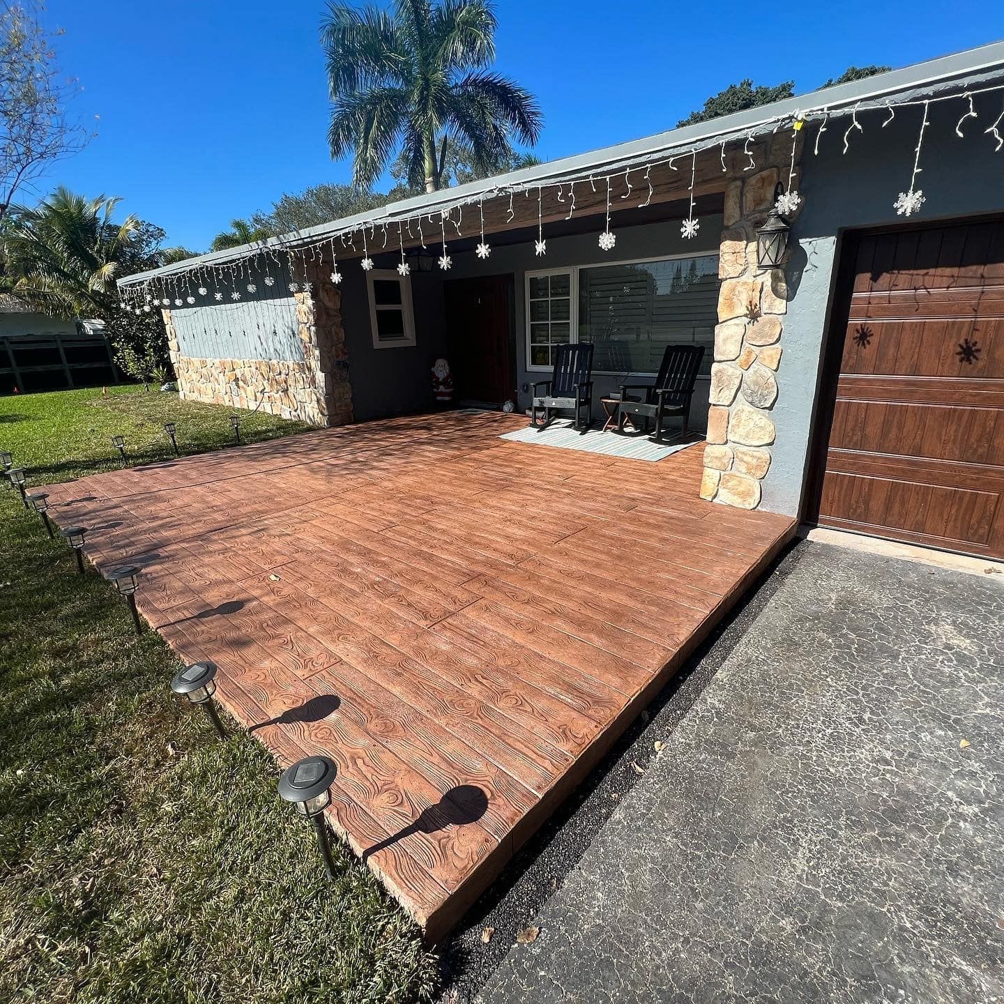 Exterior view of a house with a large wooden deck and a garage. The sky is blue.