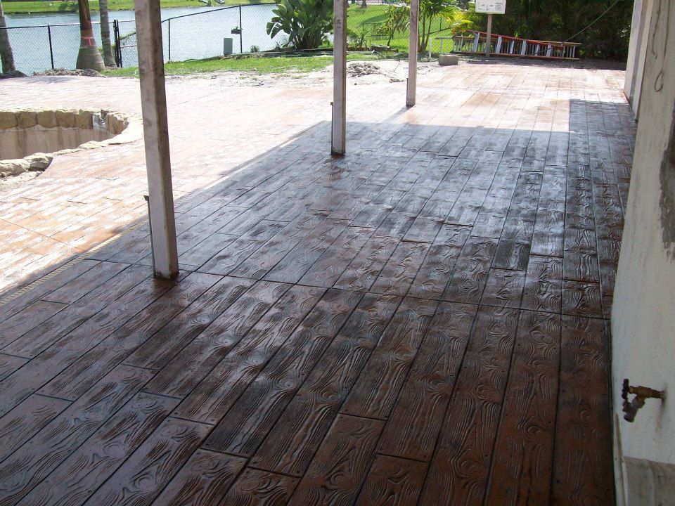 Brown stamped concrete patio, textured to resemble wood planks, under a covered area.