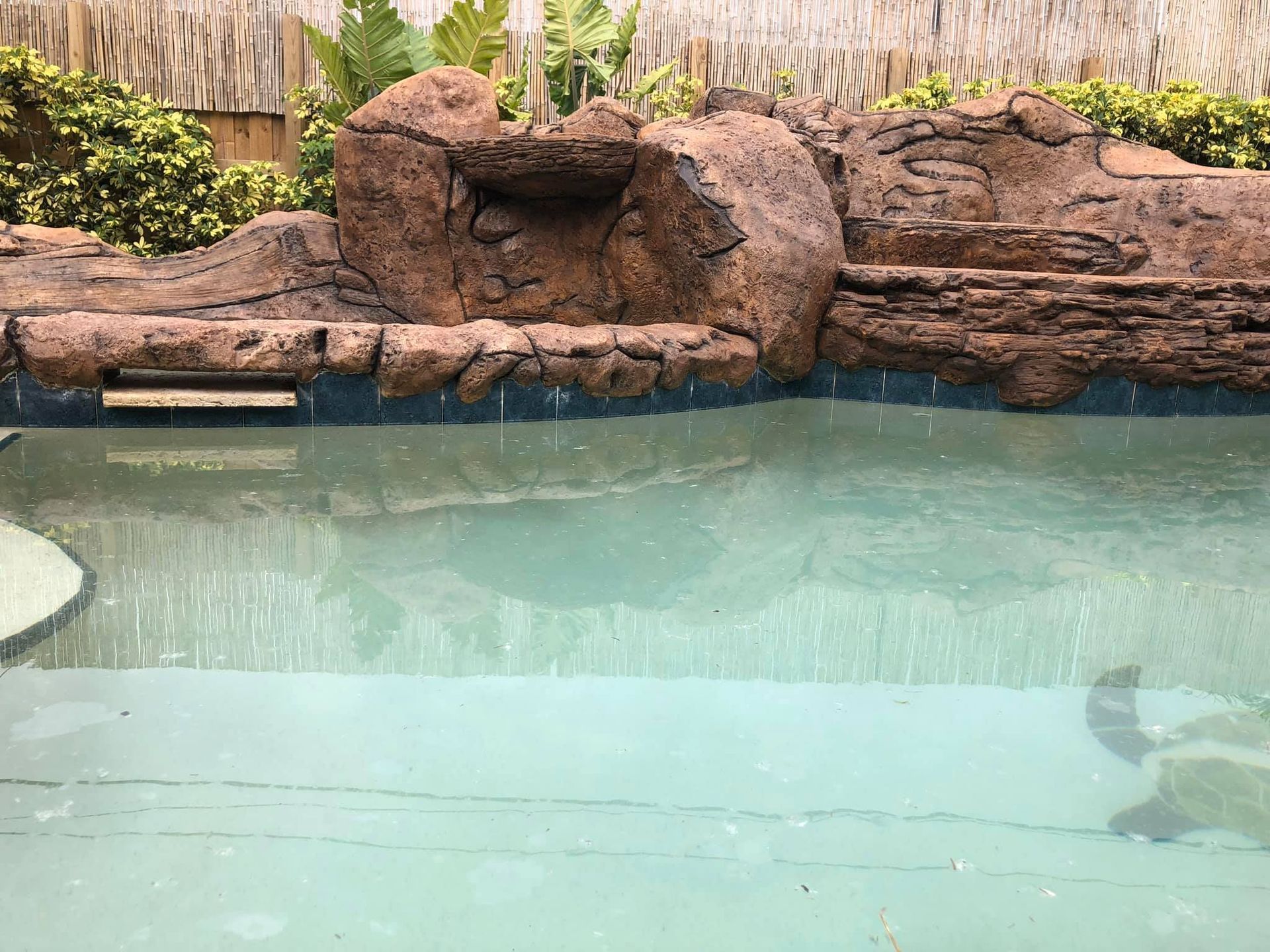 Pool with faux rock waterfall feature, light blue water.