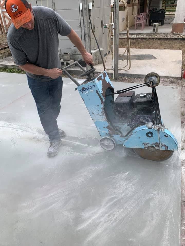Person using an angle grinder to cut concrete, creating dust.