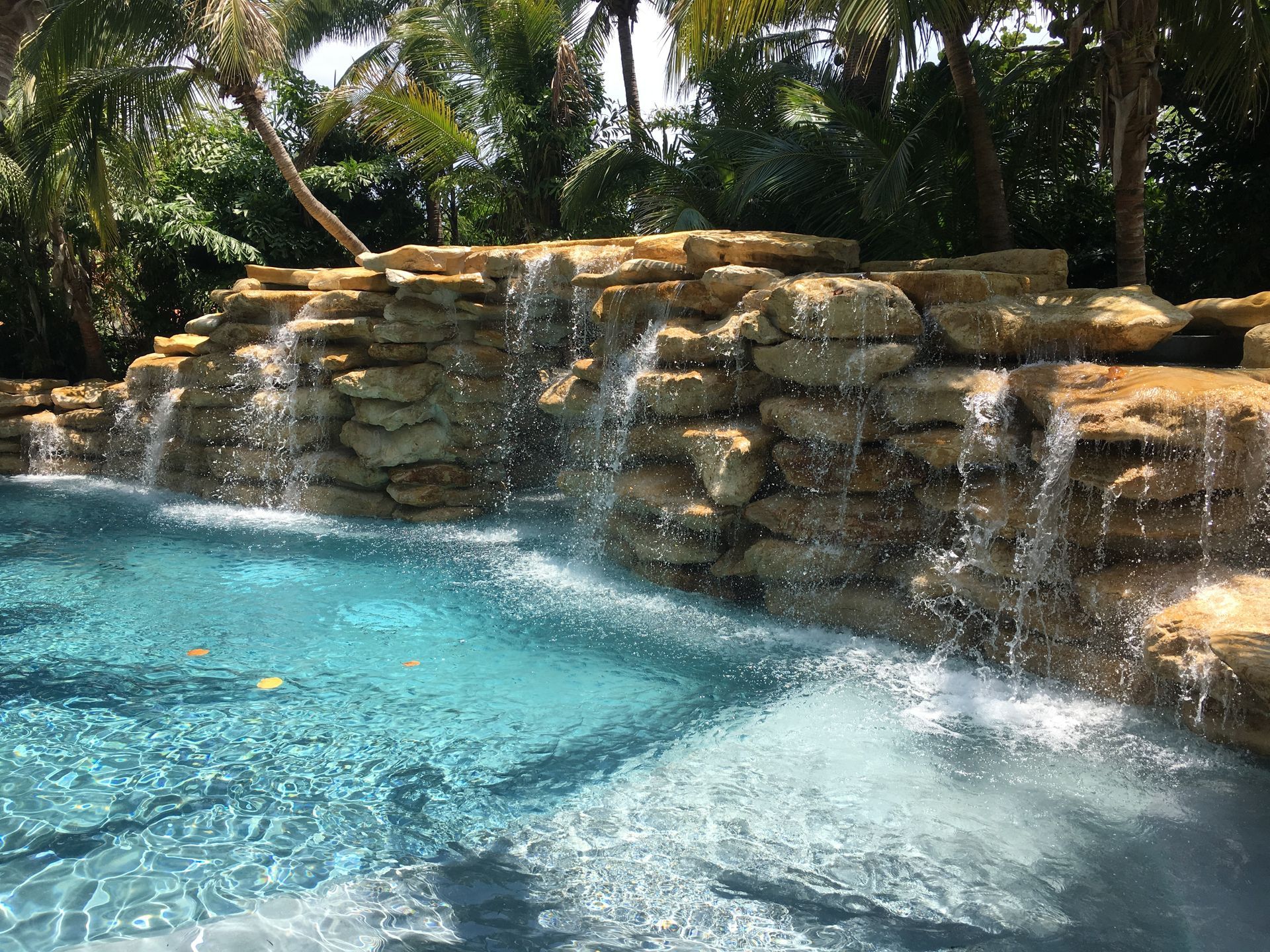 Stone steps and retaining walls with lush plants and flowers leading to a building's entrance.