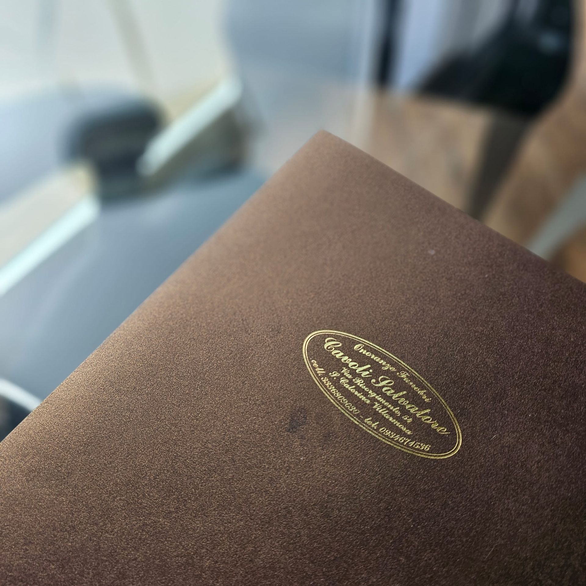 Libro con copertina marrone e etichetta ovale dorata.