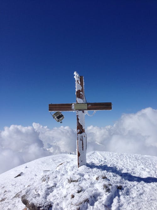 wooden cross atop snowy mountain top