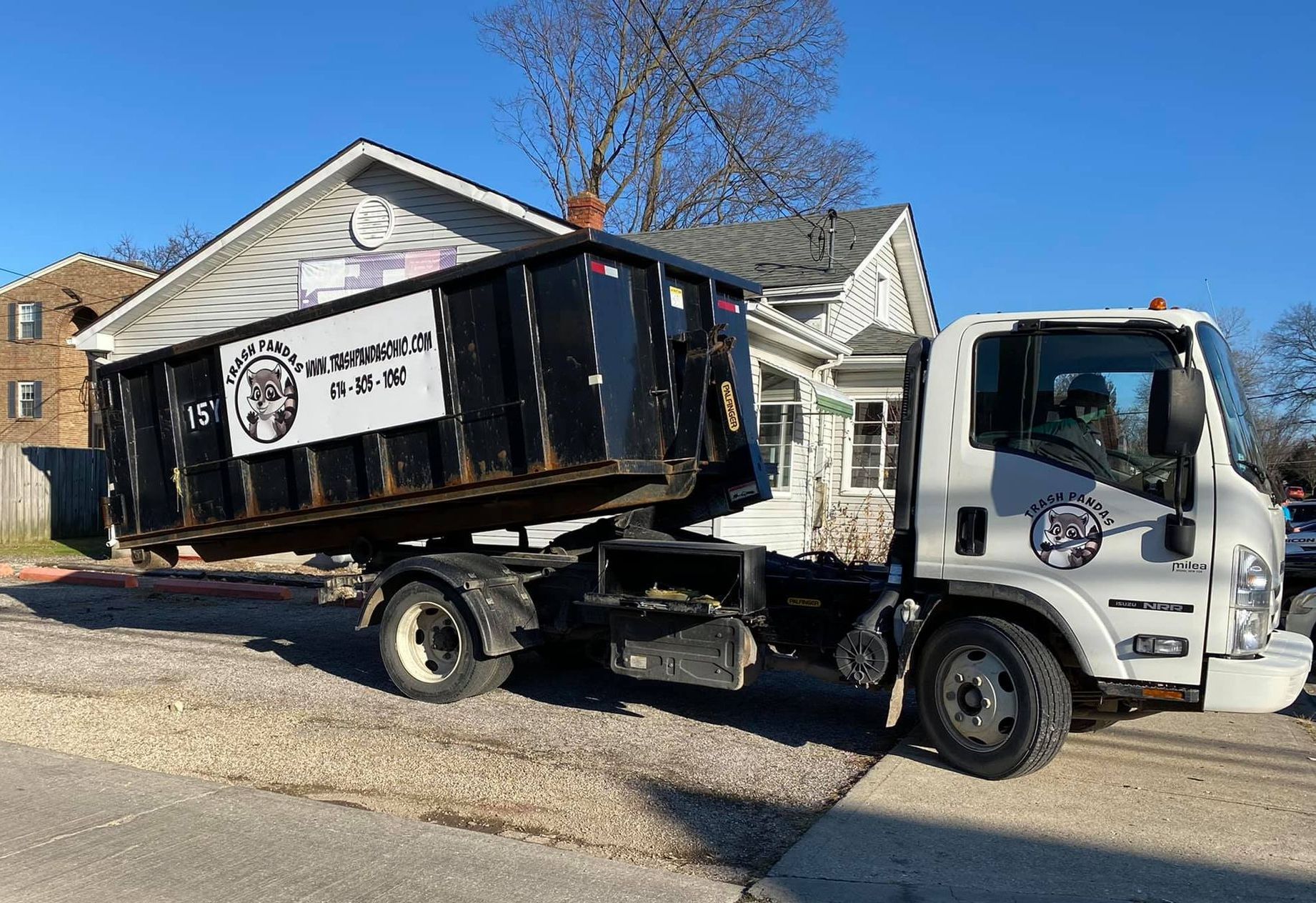 Trash Pandas Ohio roll-off truck unloading a 15-yard dumpster in a residential driveway
