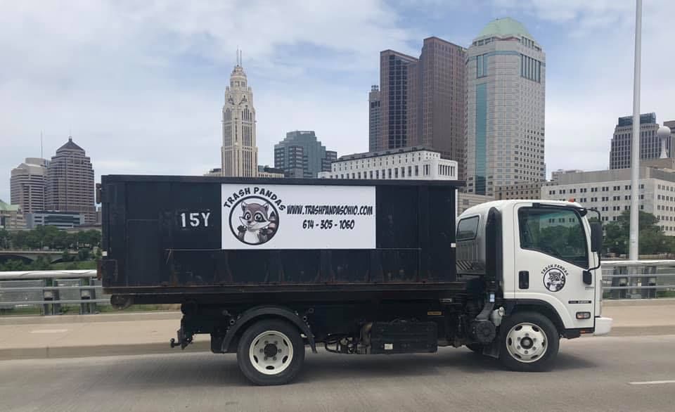 Trash Pandas Ohio 15-yard dumpster truck crossing a bridge in downtown Columbus, Ohio