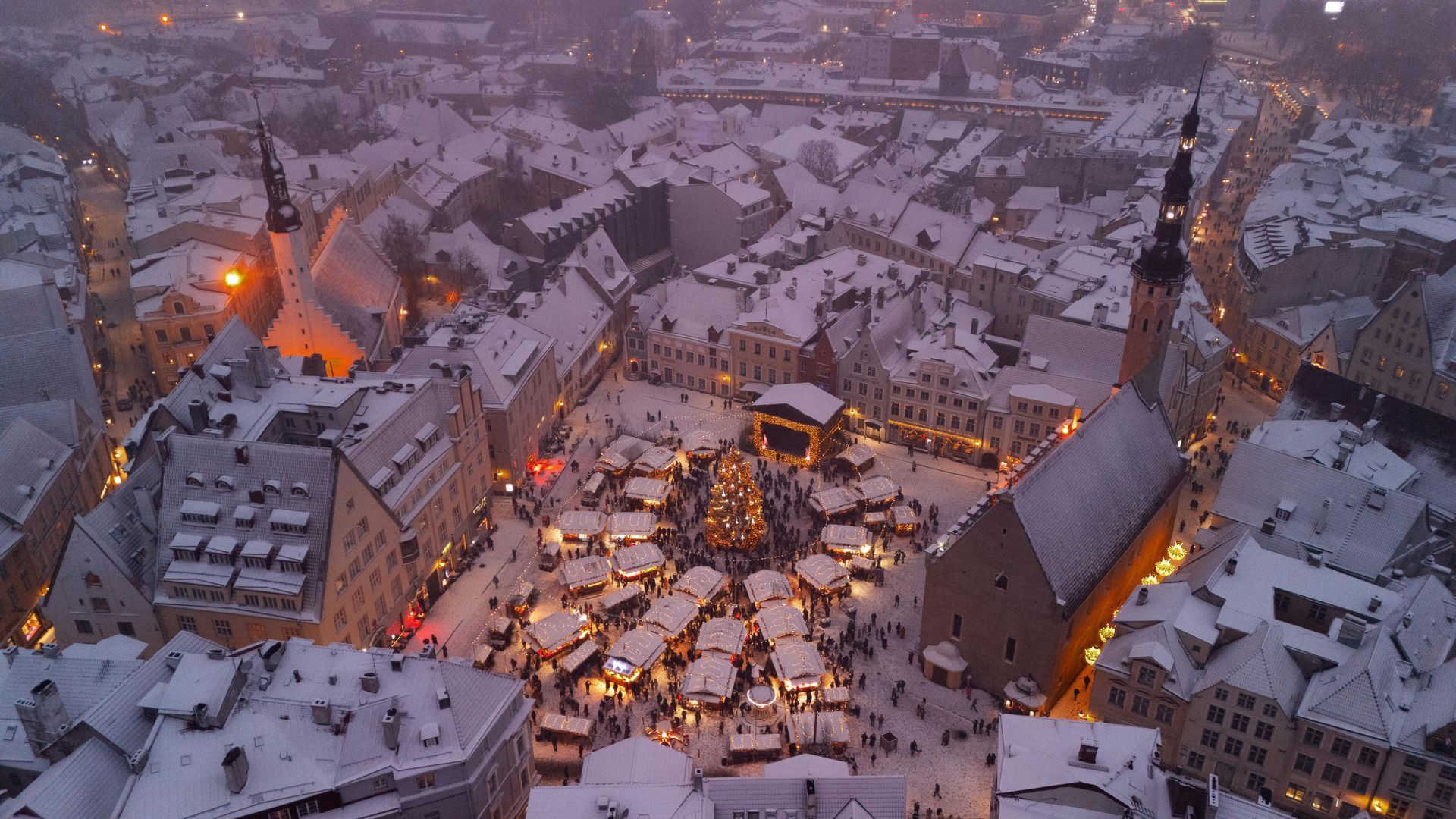 An aerial view of a christmas market in a snowy city at night.