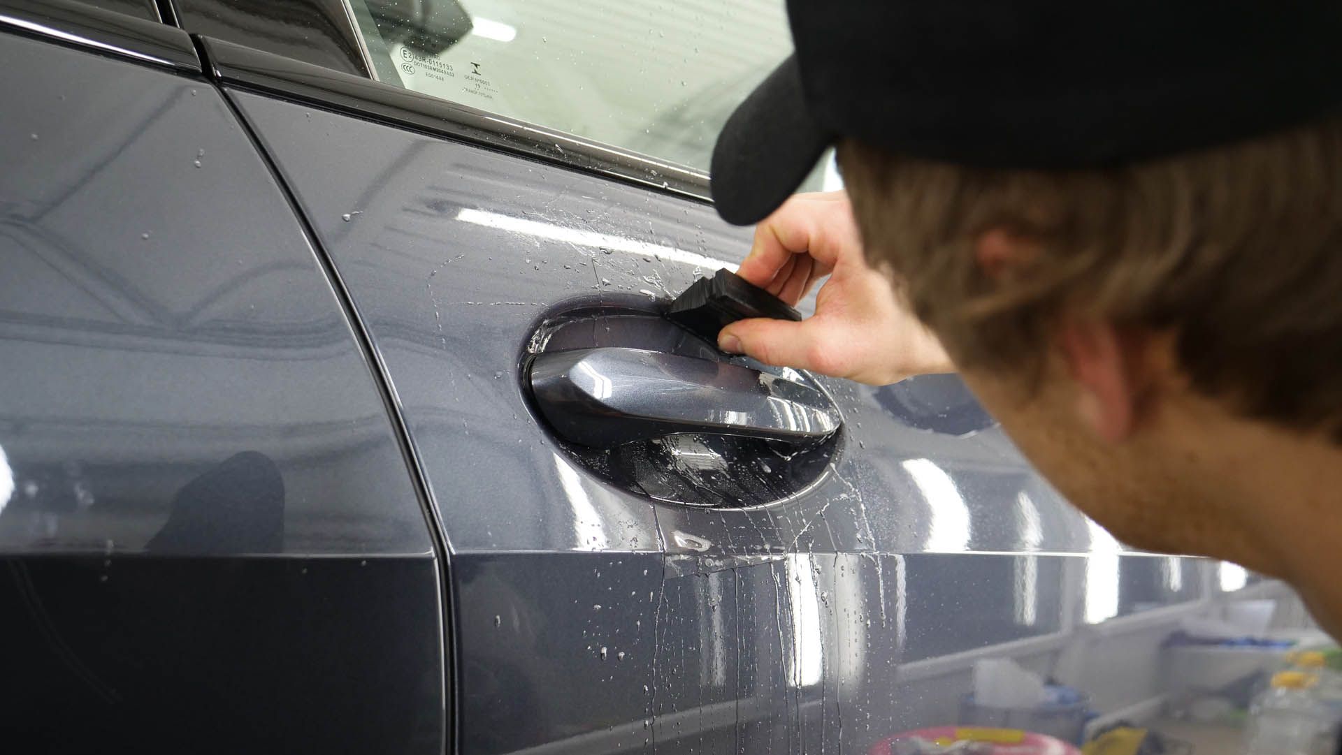 A black range rover is parked in a parking lot with palm trees in the background.