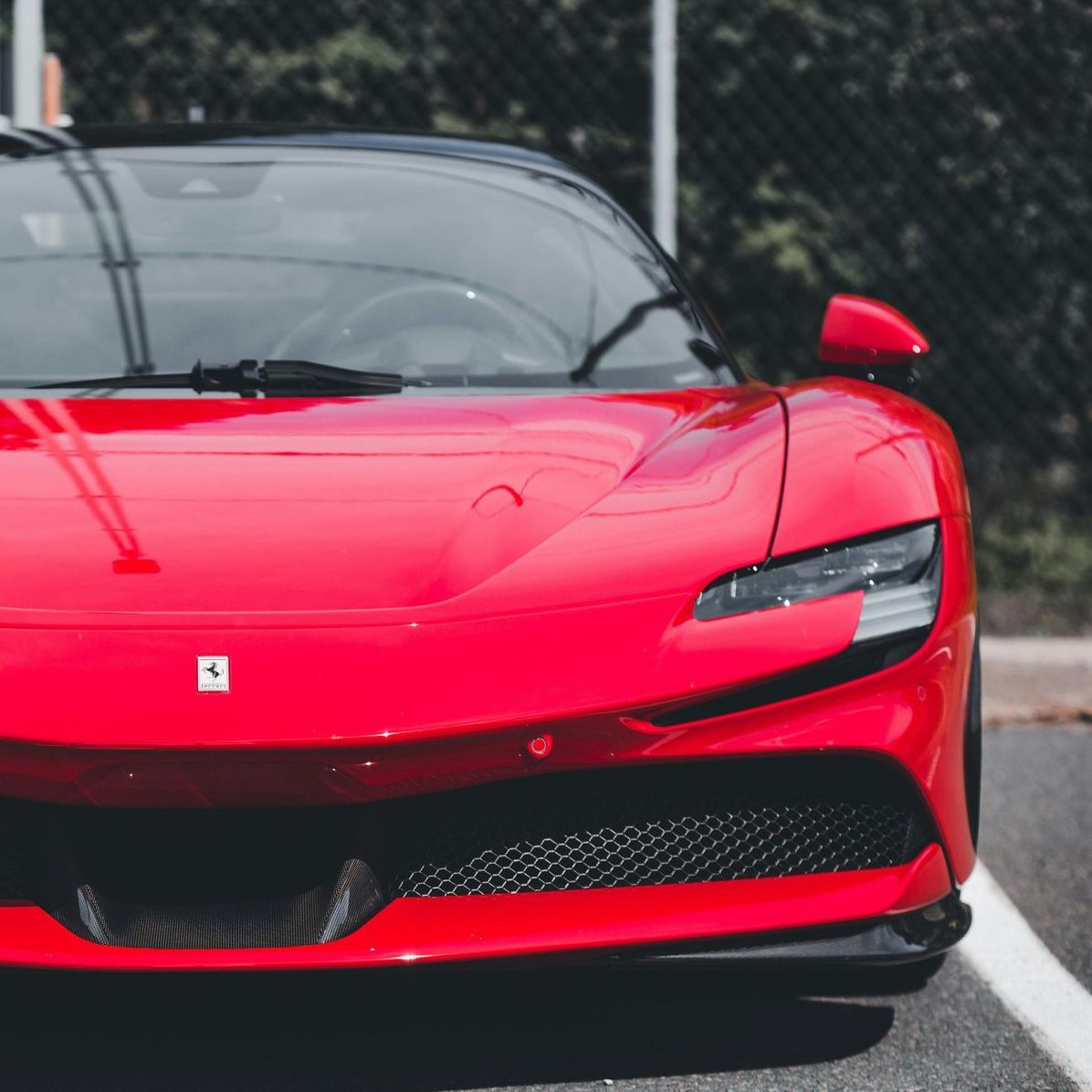 Red Ferrari sports car parked on asphalt.
