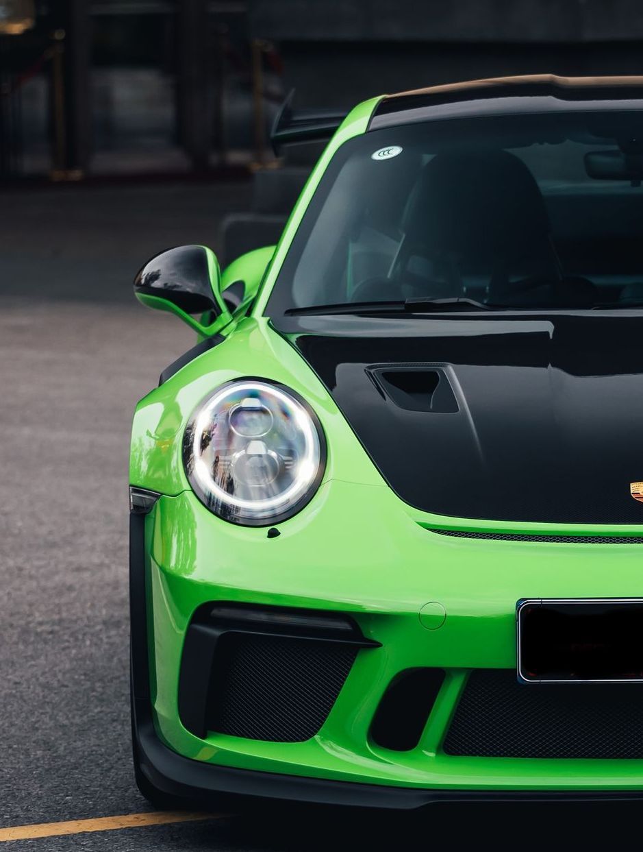 A green porsche 911 gt3 rs is parked in a parking lot.