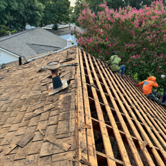 A group of people are working on the roof of a house.