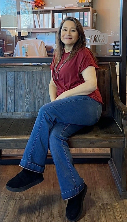 Woman in a red top and jeans sitting on a wooden bench in a cozy café.