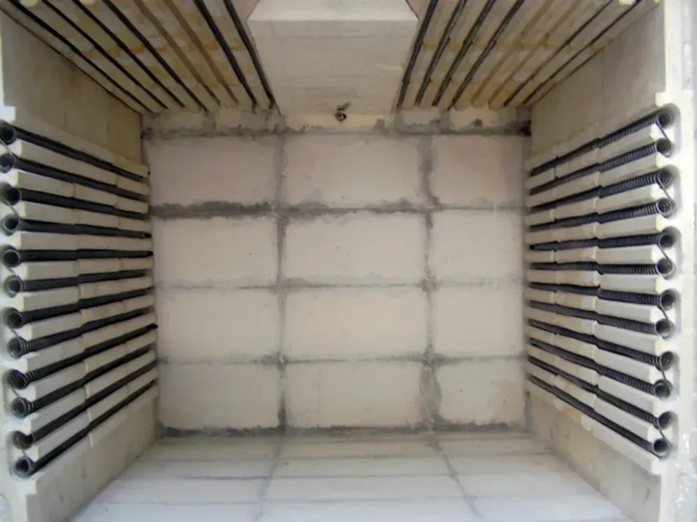 Interior de un horno con elementos calefactores negros y paredes de ladrillo blanco.