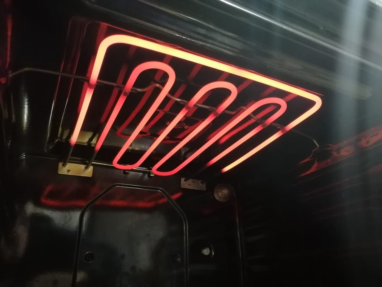 Elemento calefactor eléctrico de color rojo brillante en el interior del horno.