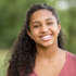 A young woman with curly hair is smiling for the camera.