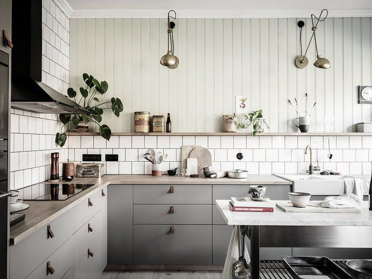 A kitchen with gray cabinets , white tiles , a sink and a stove.