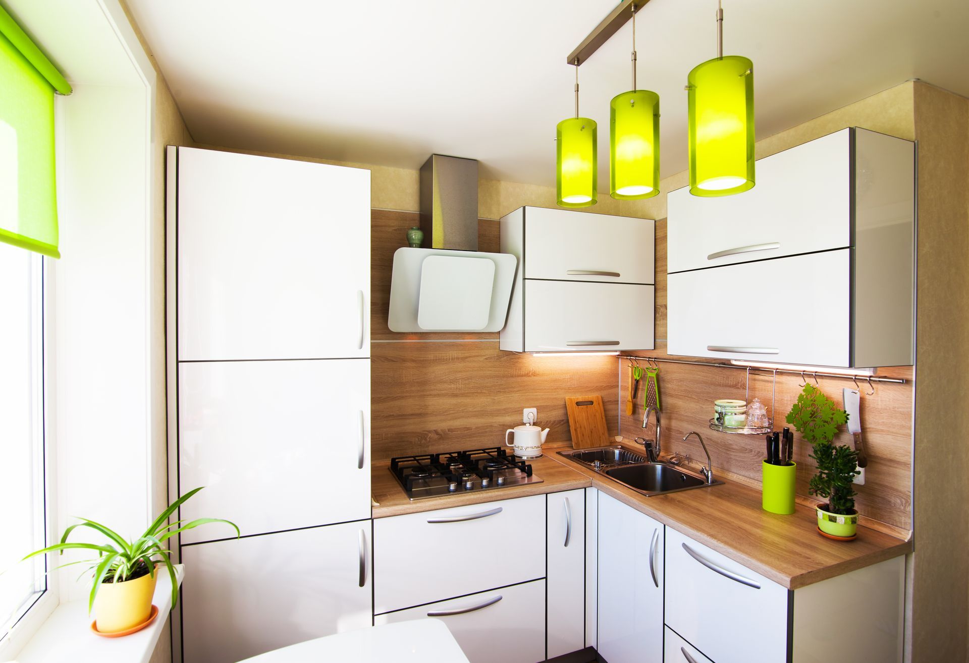 A kitchen with white cabinets and green pendant lights