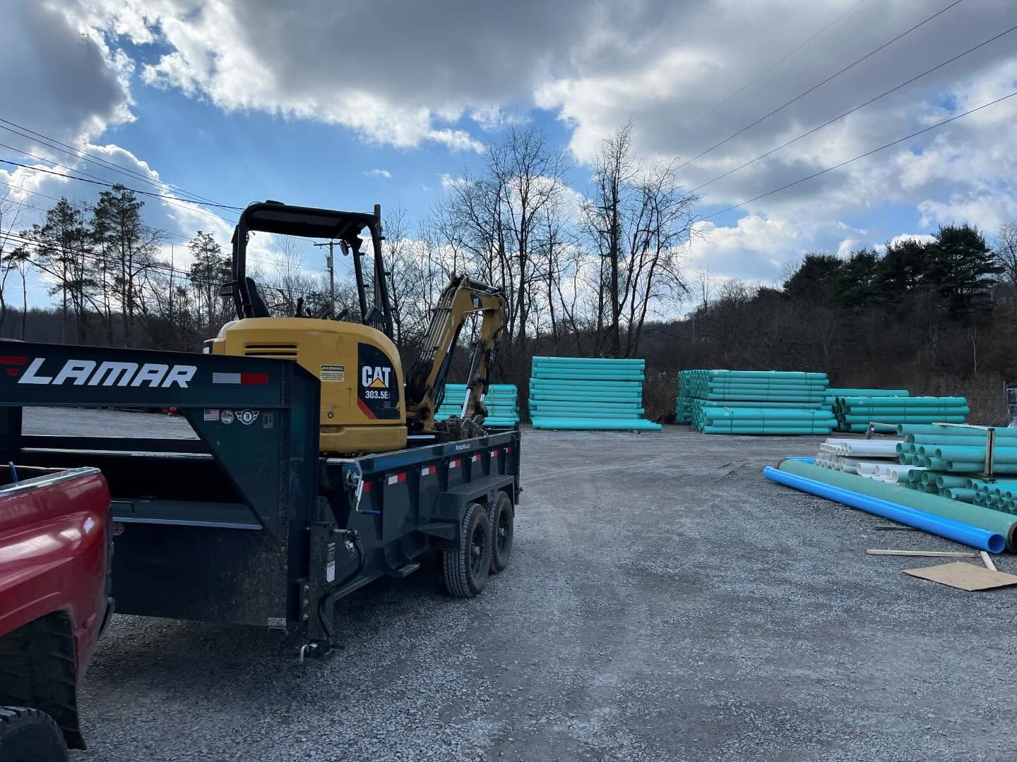 A bulldozer is parked in a gravel lot next to a truck.