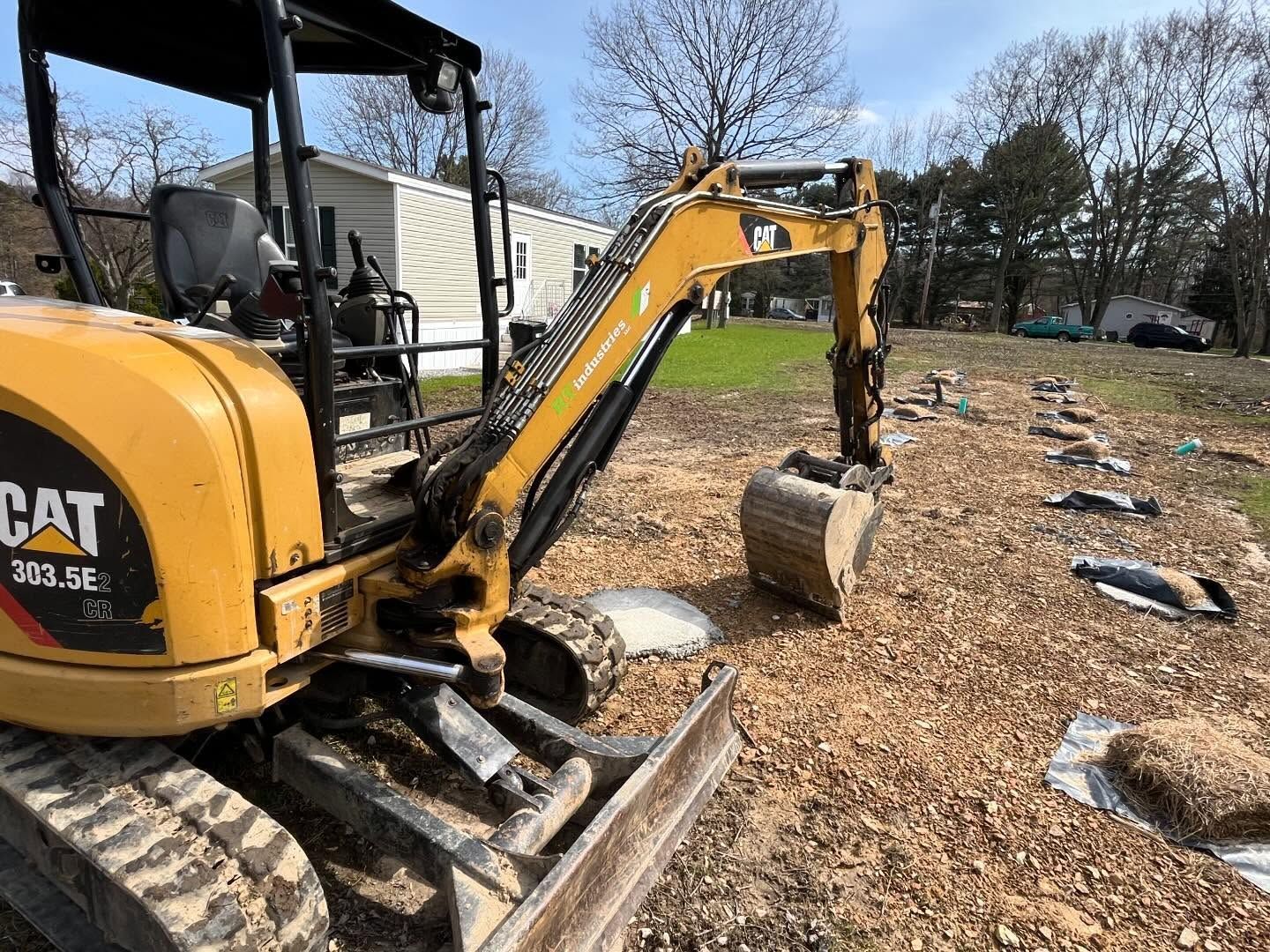 A small yellow cat excavator is sitting in a dirt field.