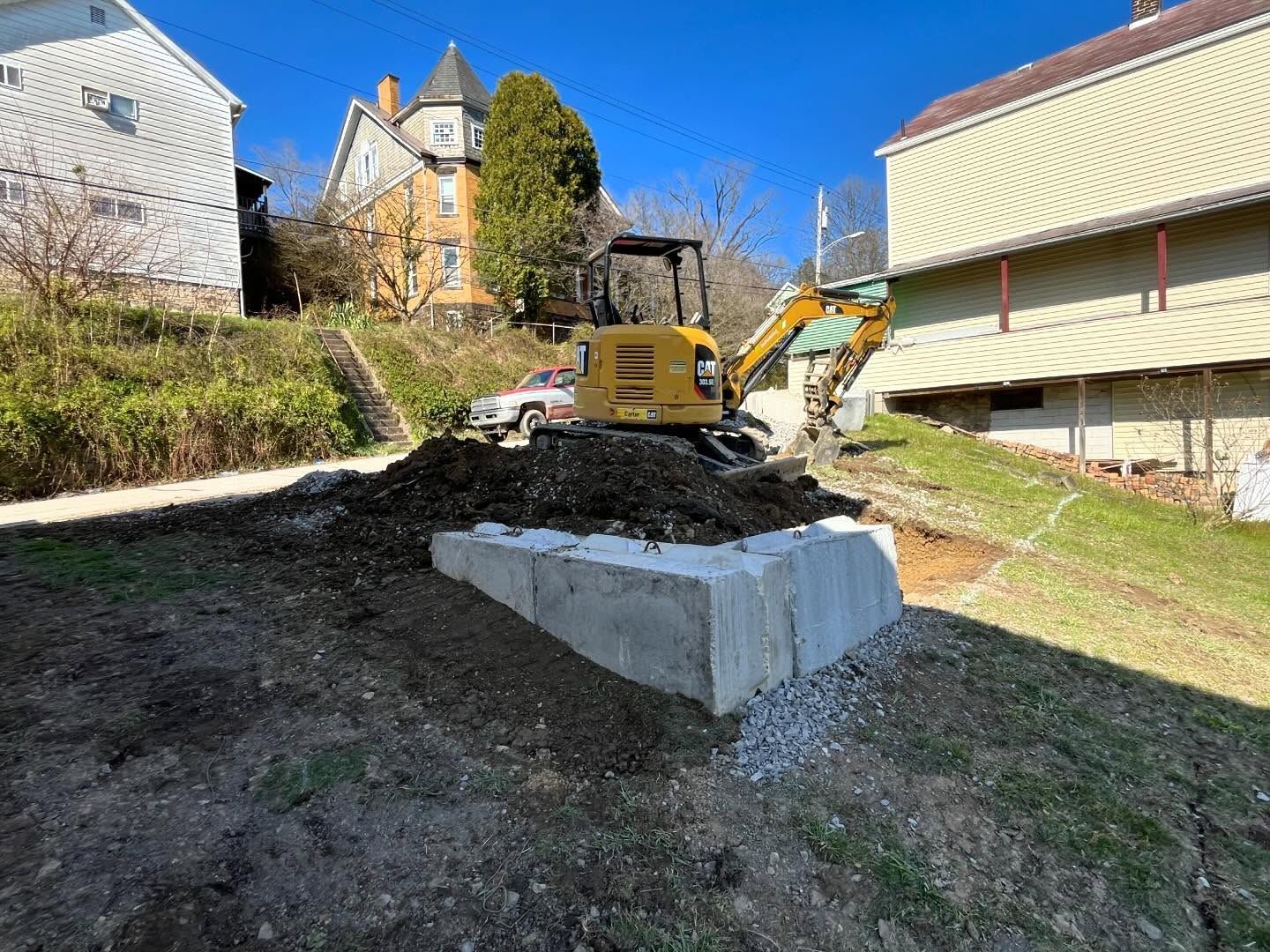 A bulldozer is digging a hole in a yard in front of a house.