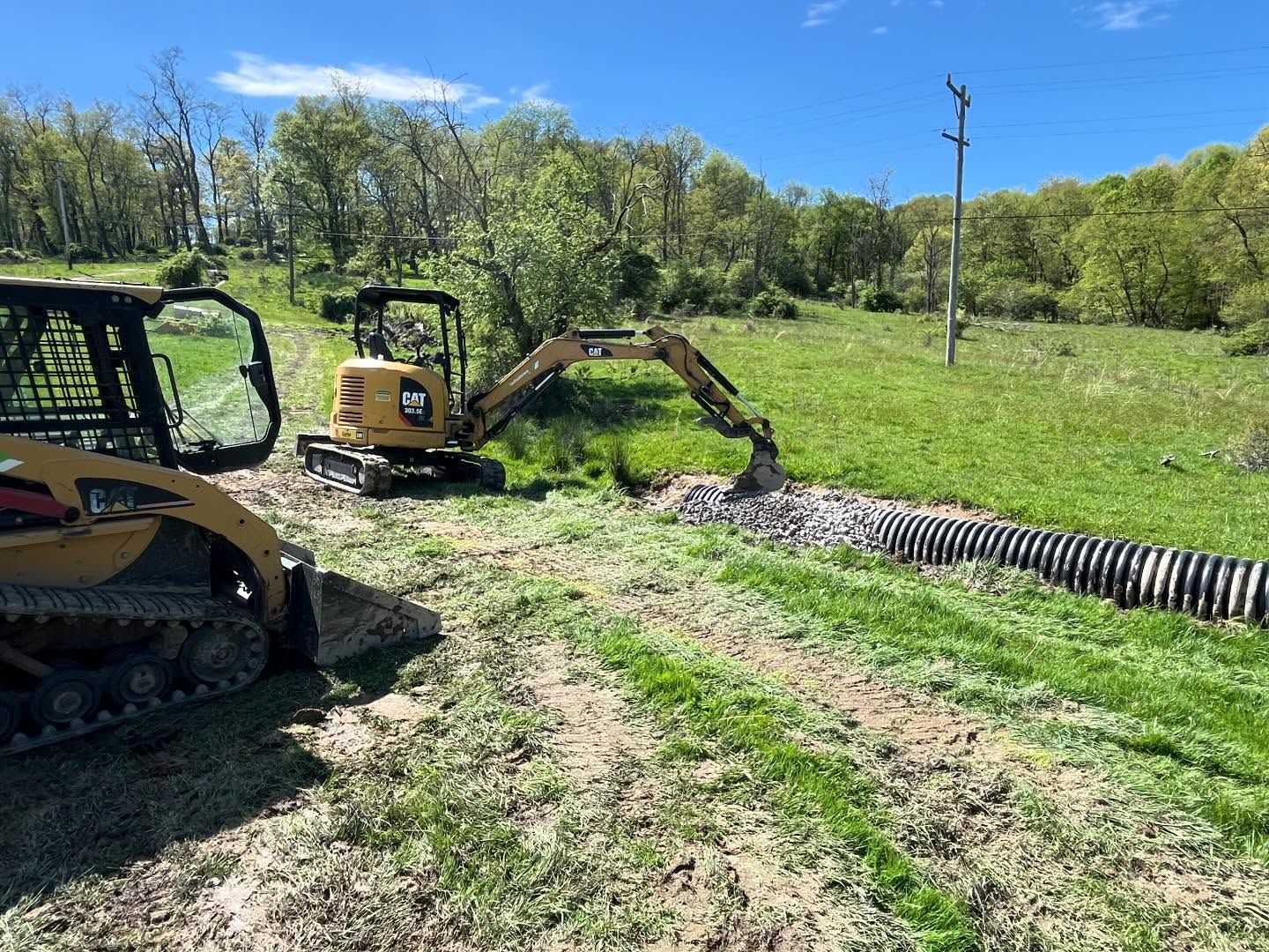 A small excavator is digging a hole in a grassy field.