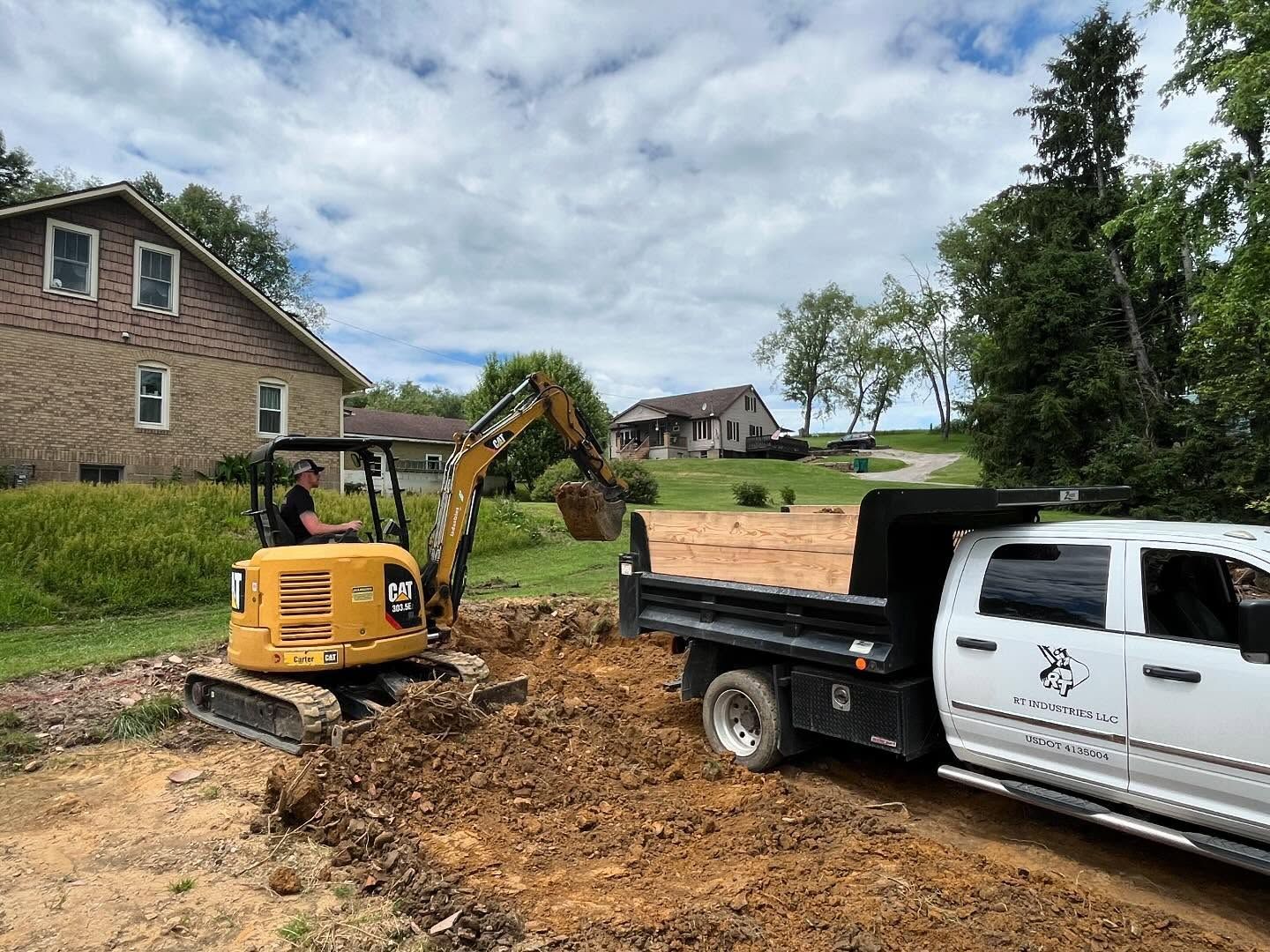 A man is driving an excavator next to a dump truck.