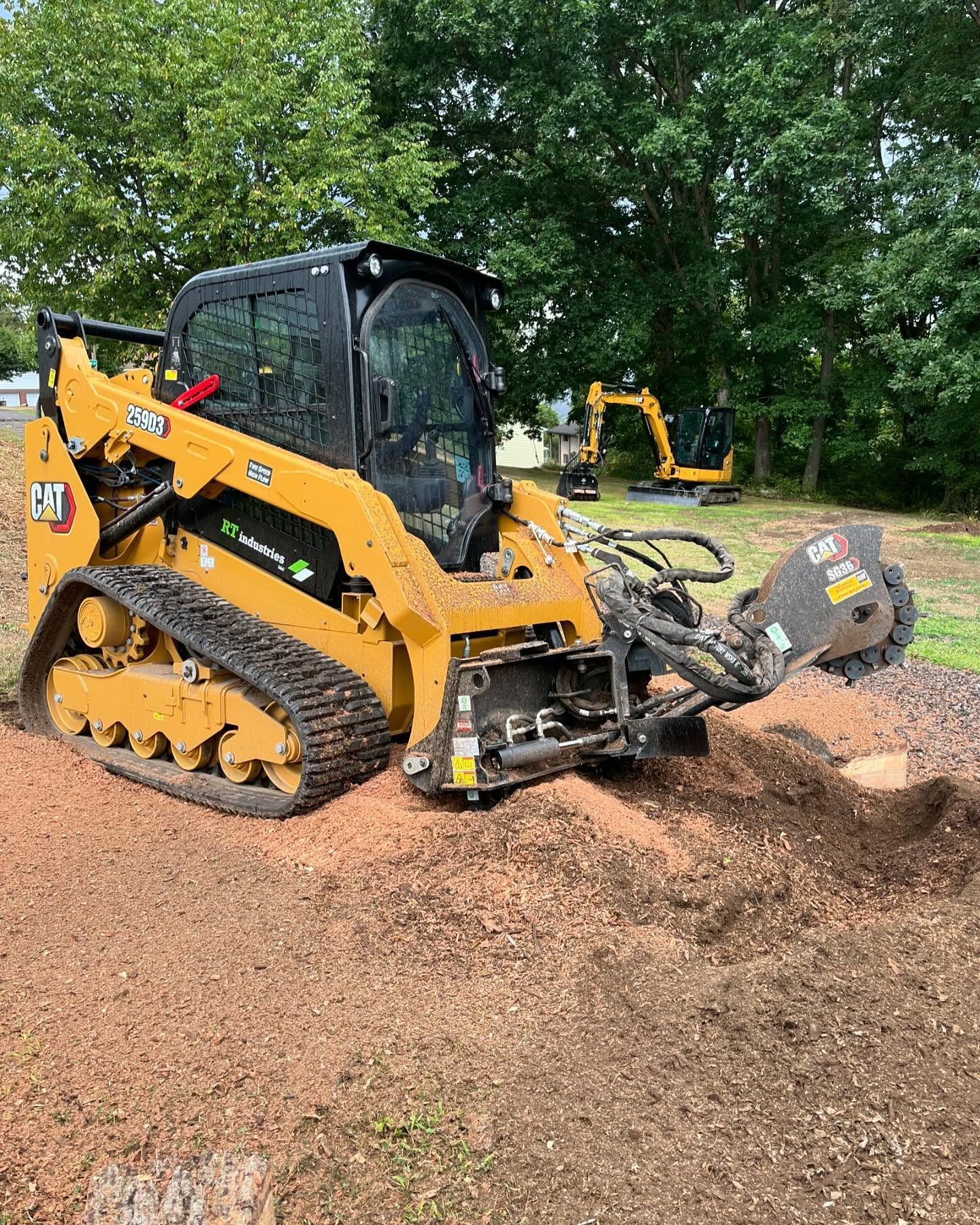 A bulldozer is cutting a tree stump in a field.