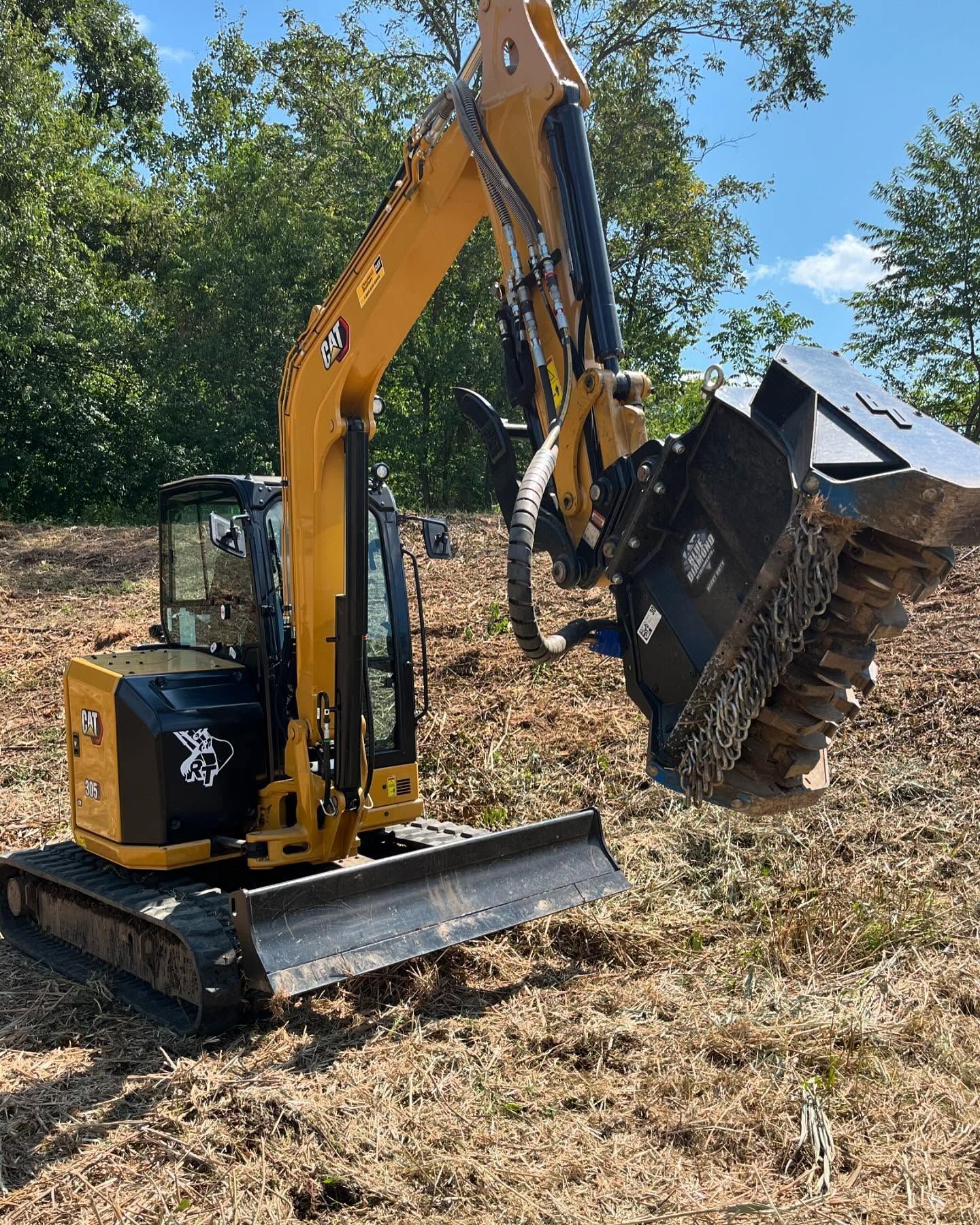 A yellow and black excavator is sitting in a field.