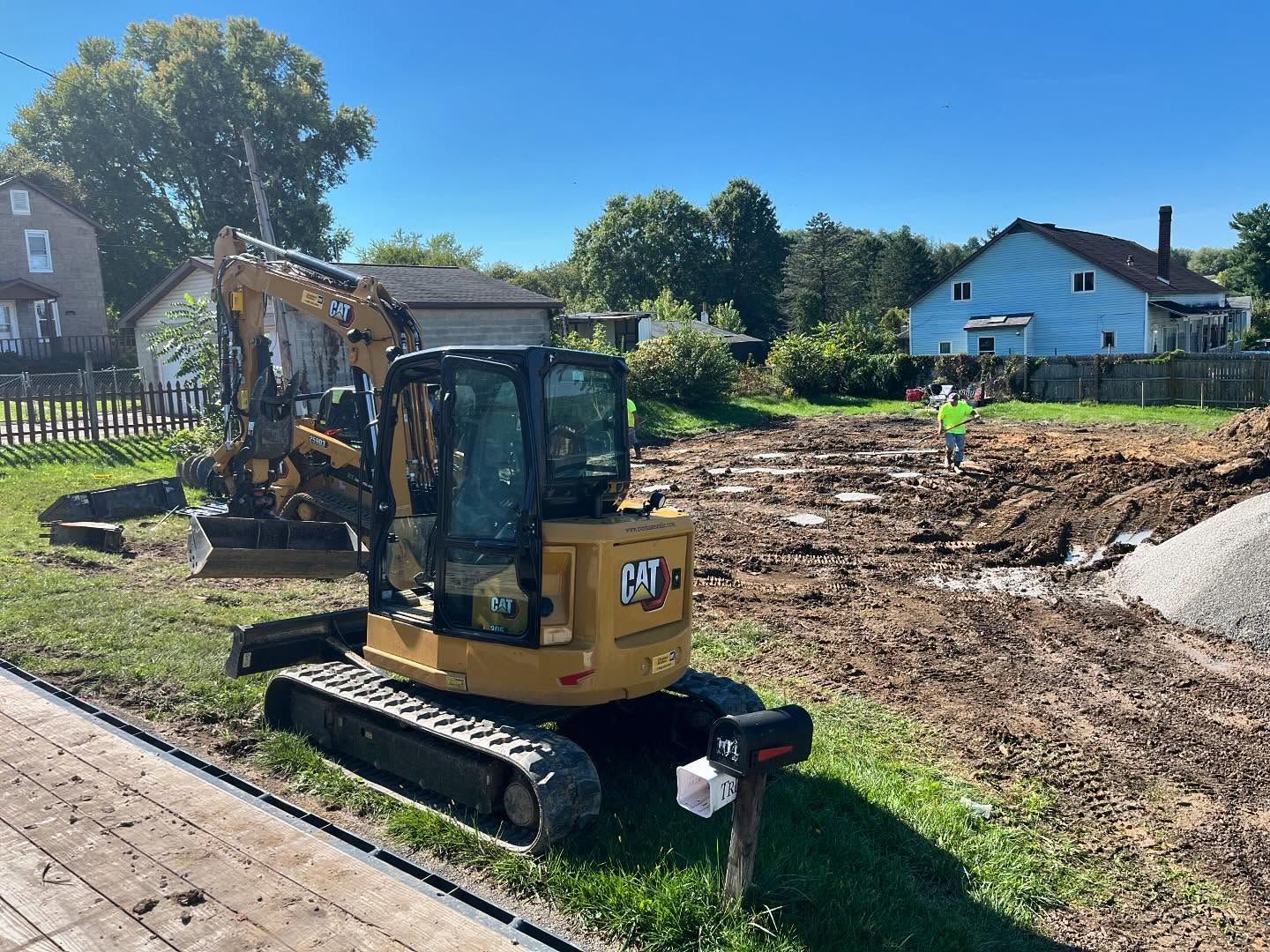 A cat excavator is parked on the side of a dirt road.