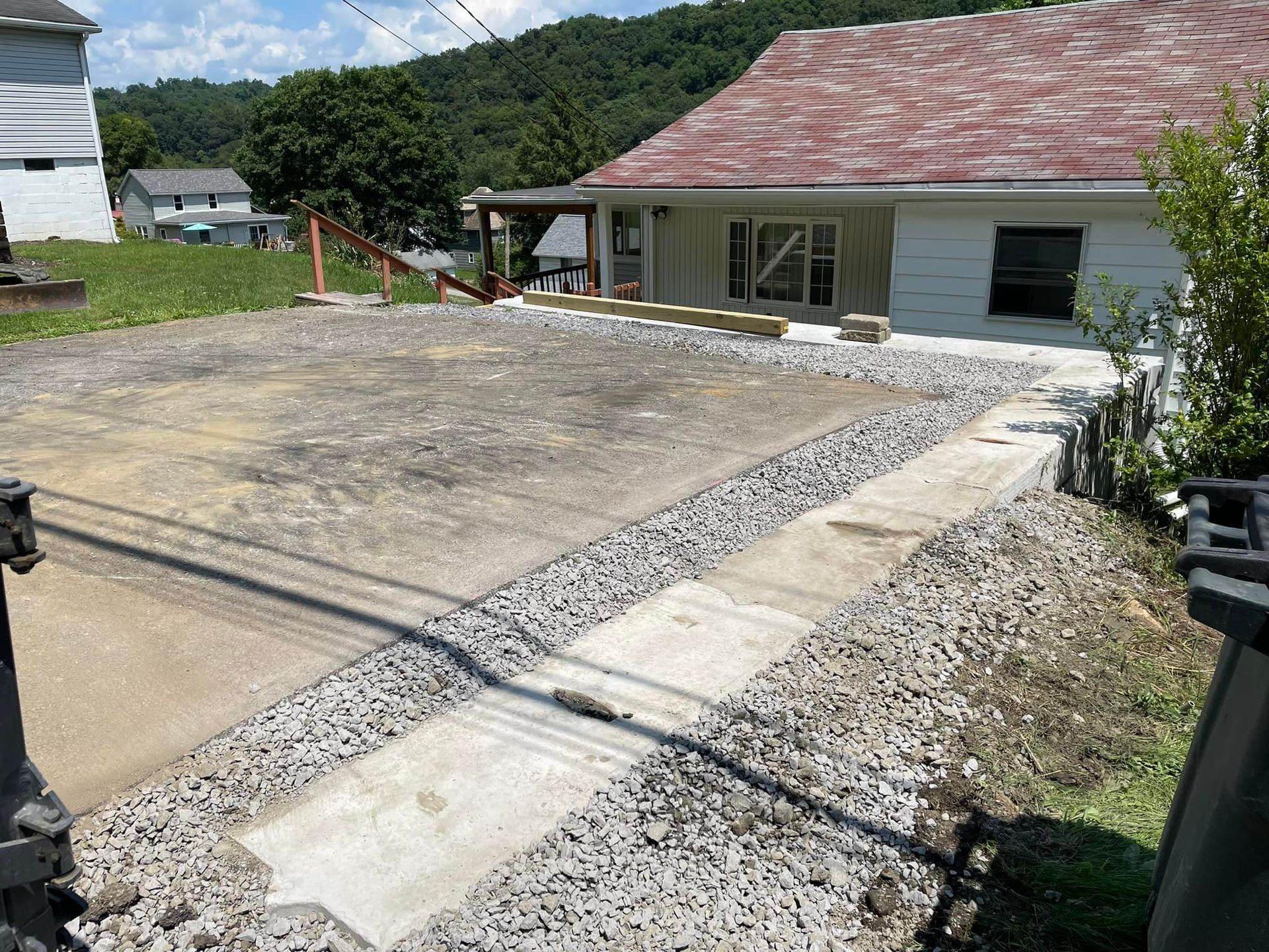 A house with a red roof and a gravel driveway in front of it.