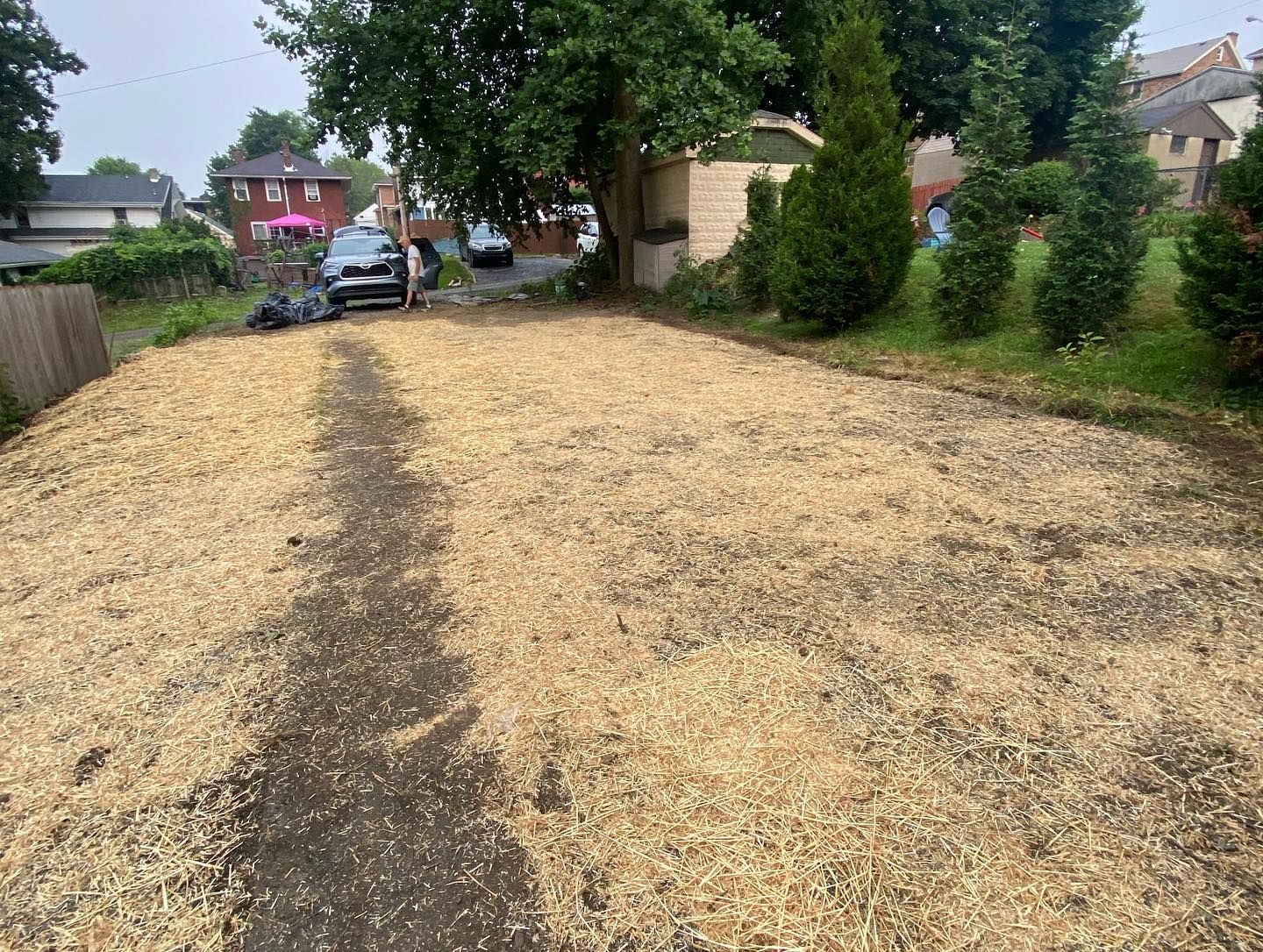 A car is parked on the side of a dirt road.