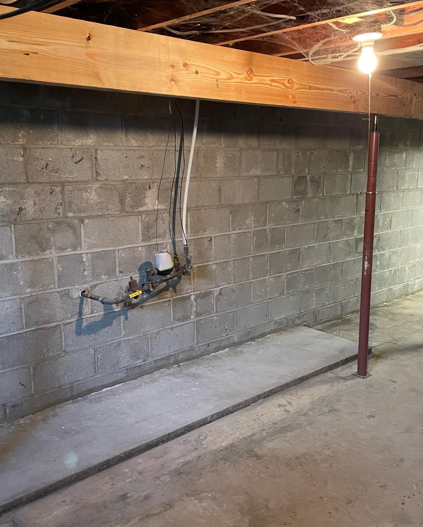 A basement with a brick wall and a wooden beam.