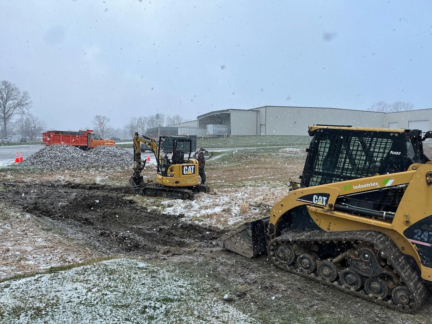 Two bulldozers are digging a hole in the snow.