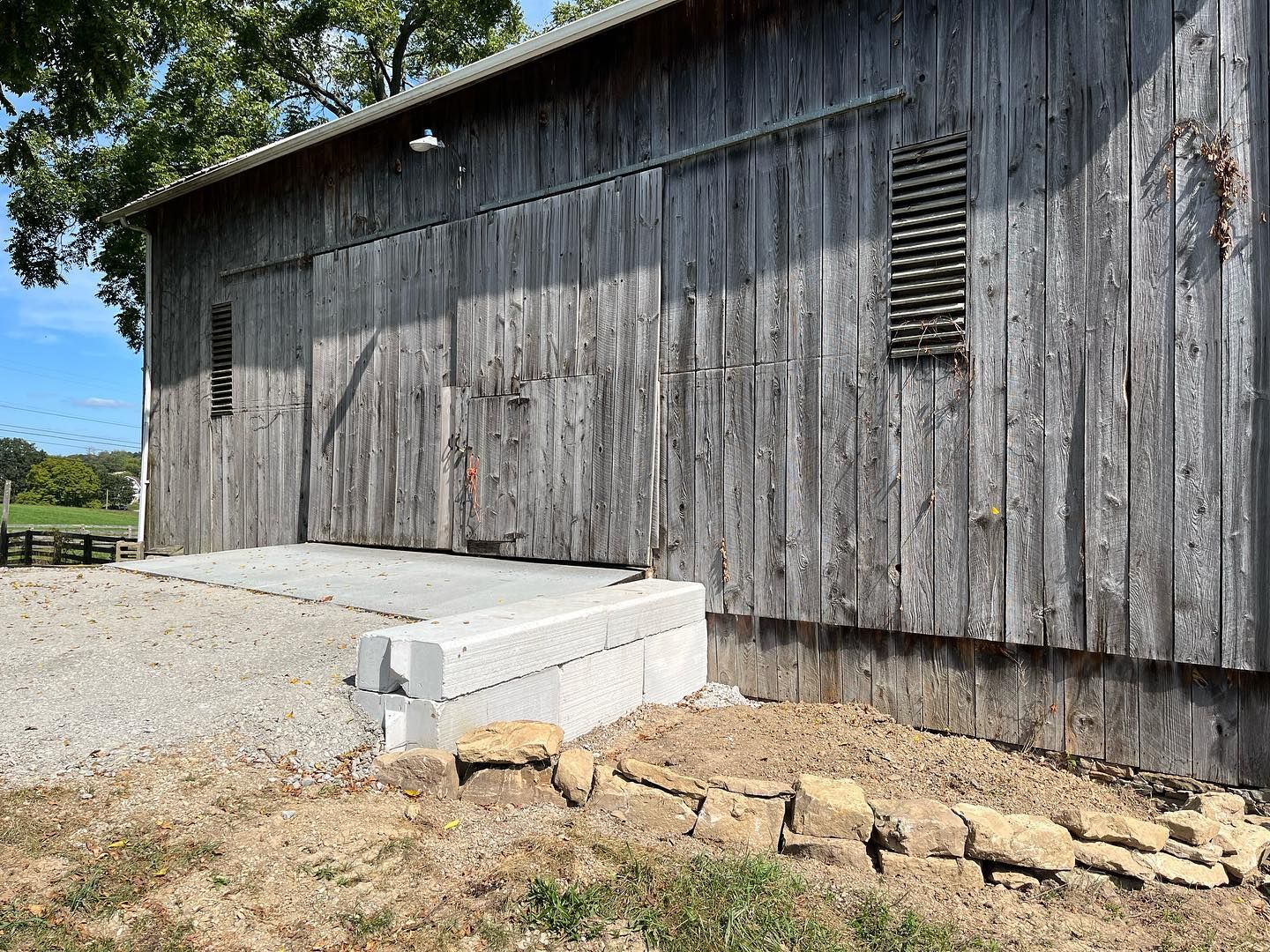 A large wooden barn with a concrete ramp in front of it.