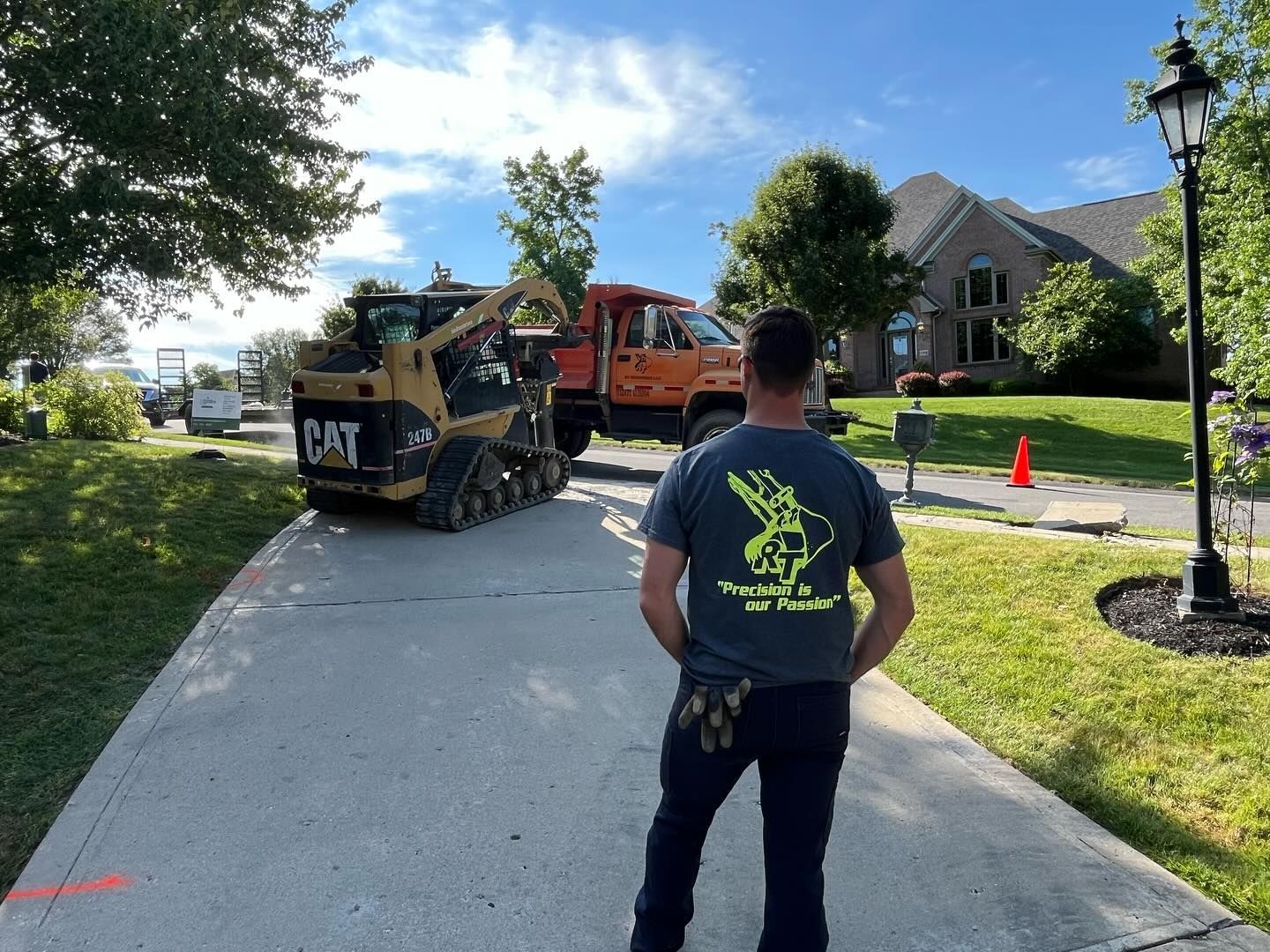 A man is standing on a sidewalk in front of a construction vehicle.