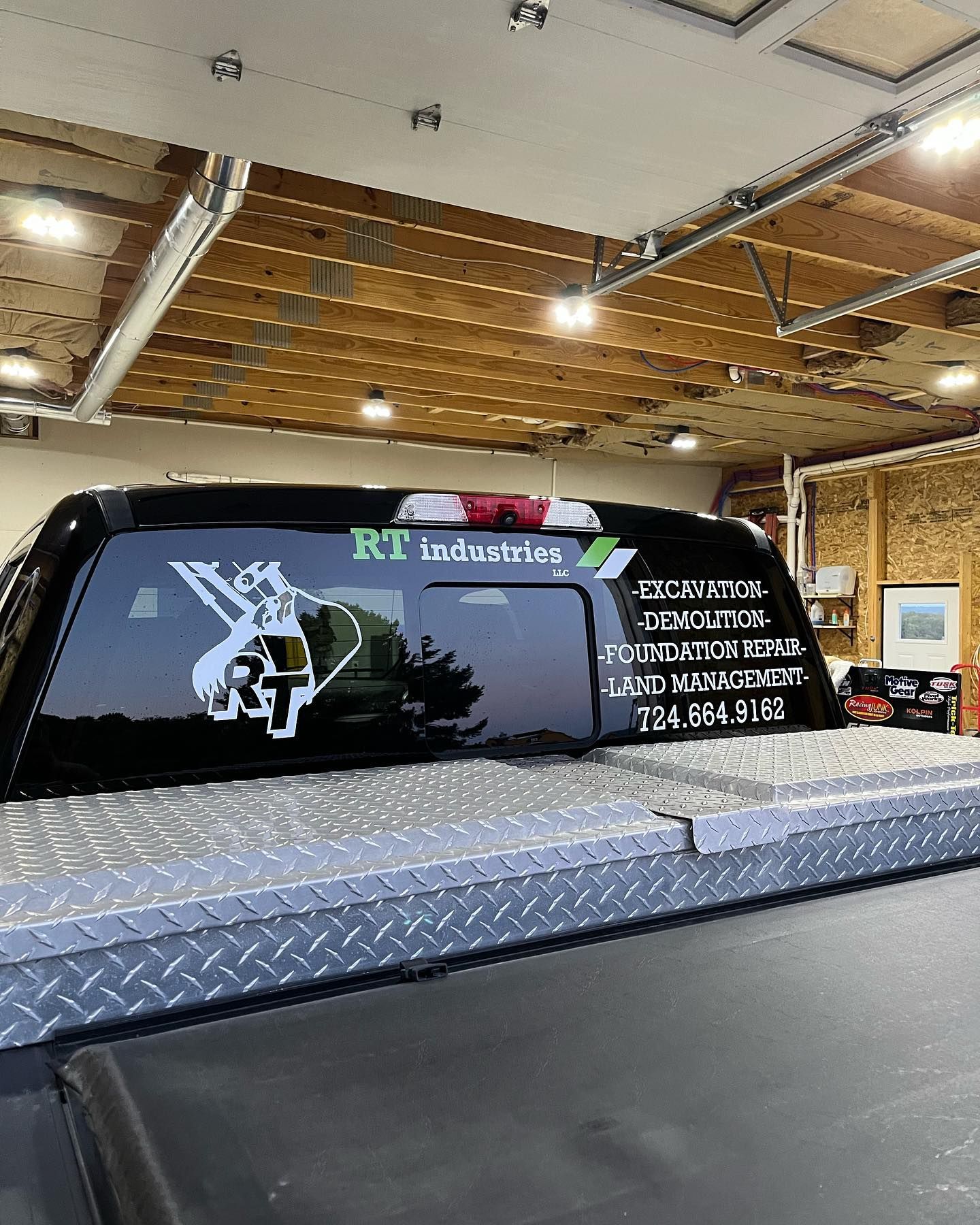 A truck with a sticker on the back window is parked in a garage.