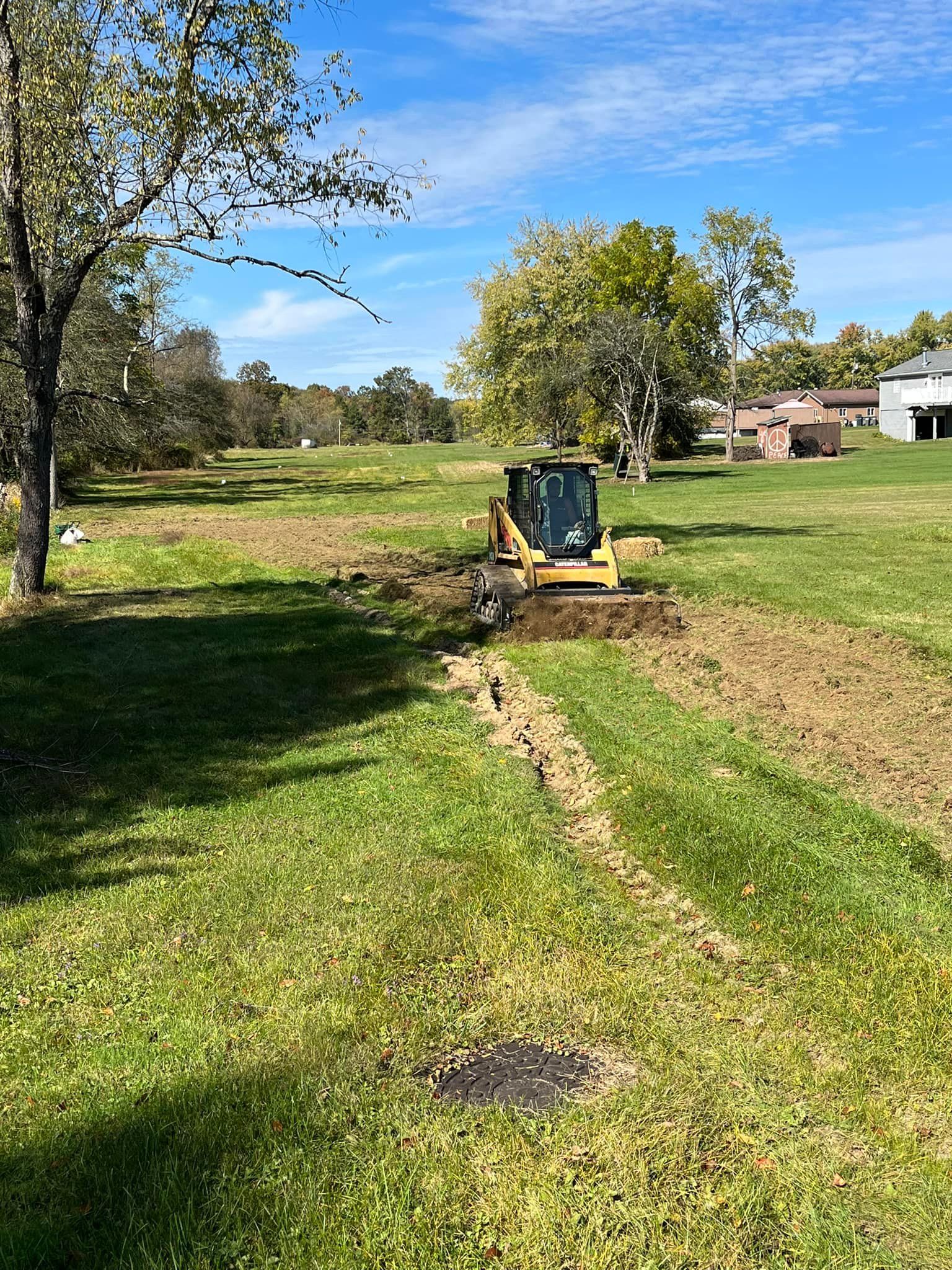 A bulldozer is digging a hole in the grass in a field.
