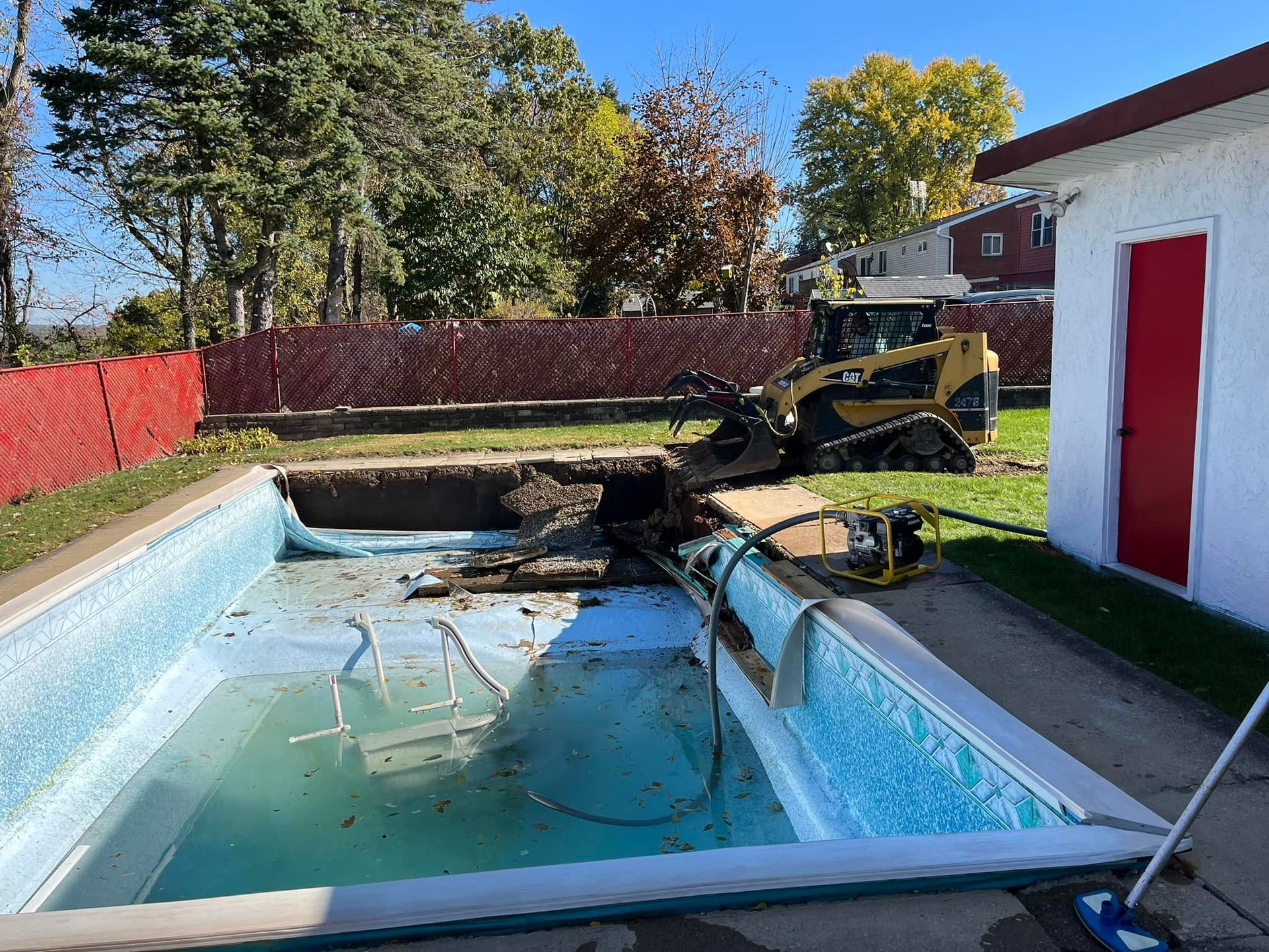 An empty swimming pool with a bulldozer in the background.