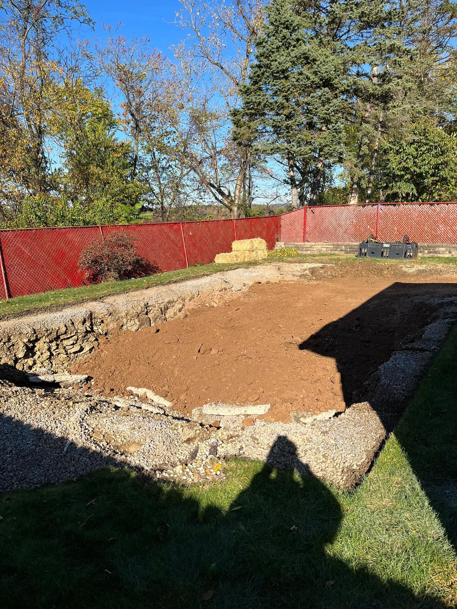 A shadow of a person is cast on the ground in a backyard.