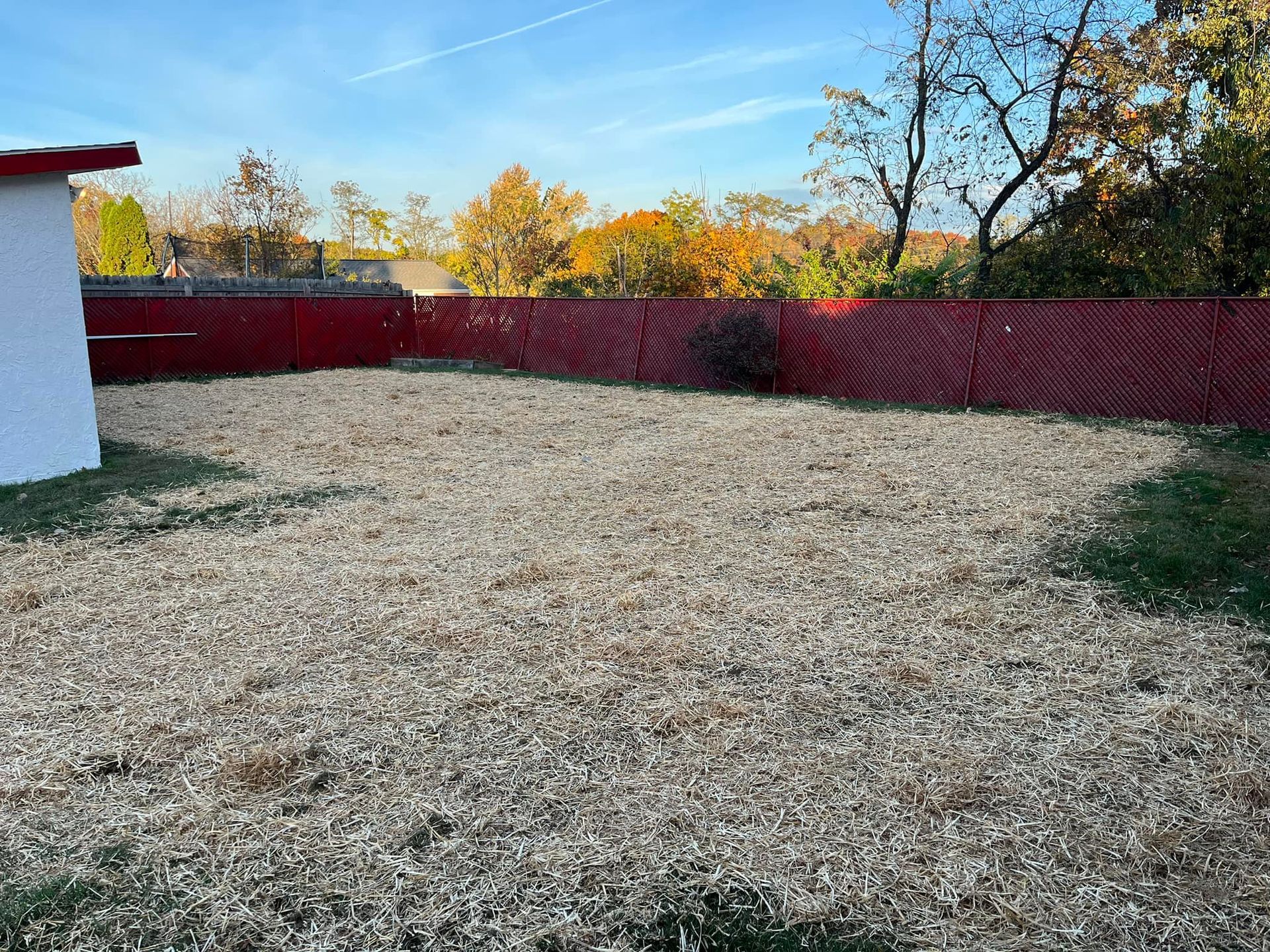 A large gravel area with a red fence in the background.