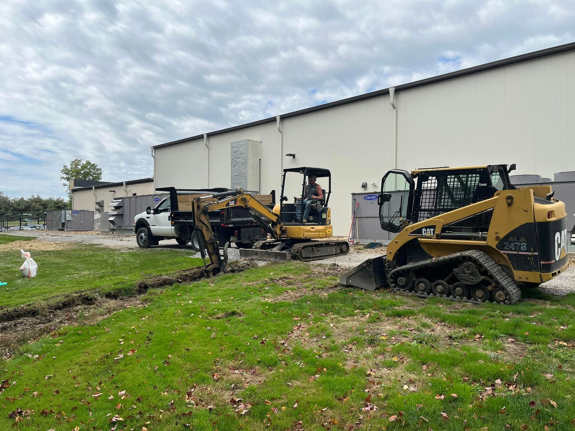 A bulldozer and a dump truck are parked in front of a building.