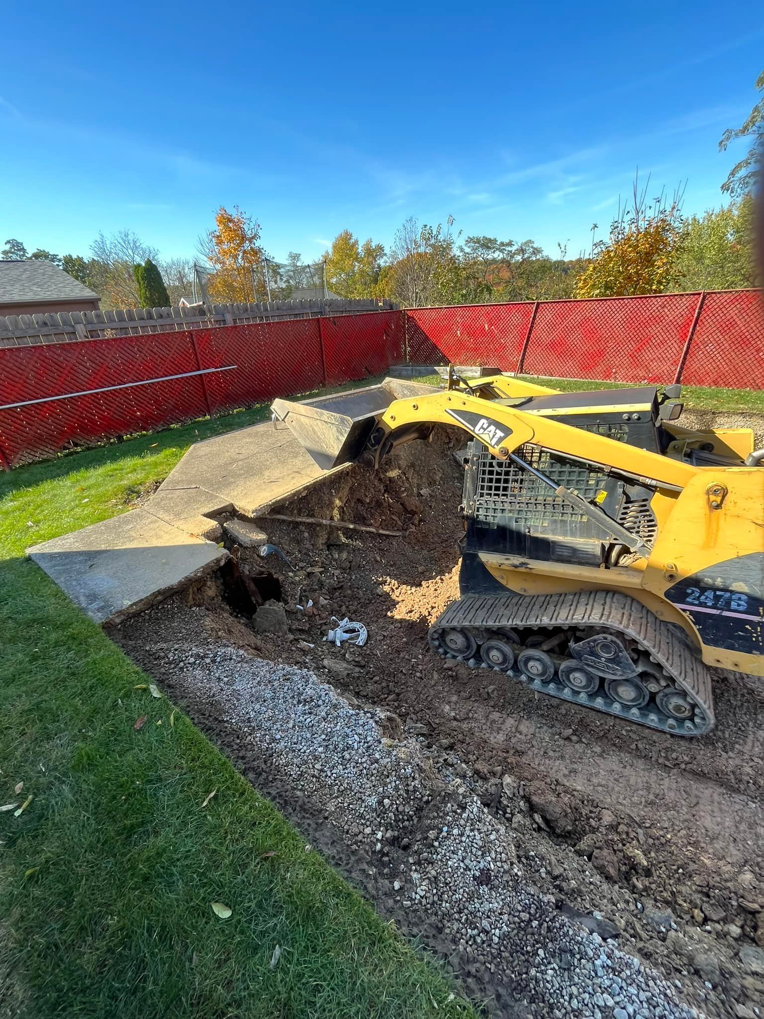A bulldozer is digging a hole in the ground in a yard.