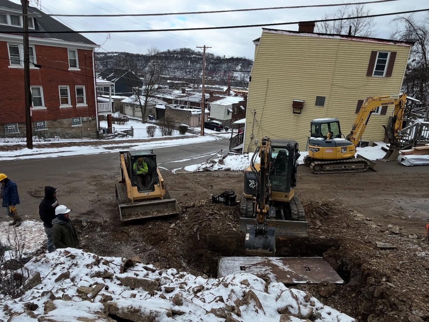 A group of construction workers are working on a construction site in the snow.