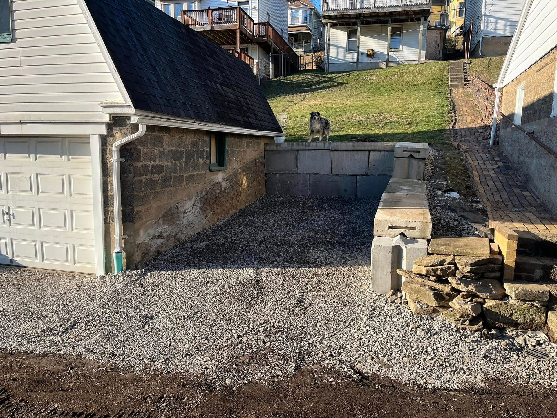 A white house with a black roof is sitting next to a gravel driveway.