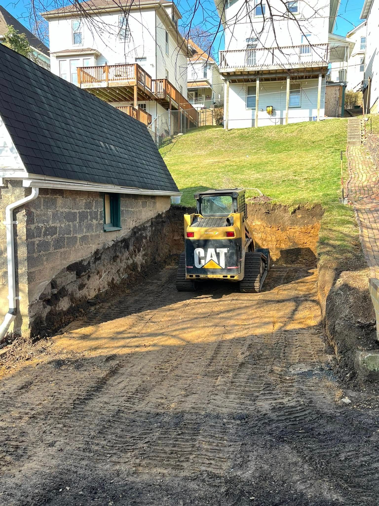 A bulldozer is digging a hole in the dirt in front of a house.
