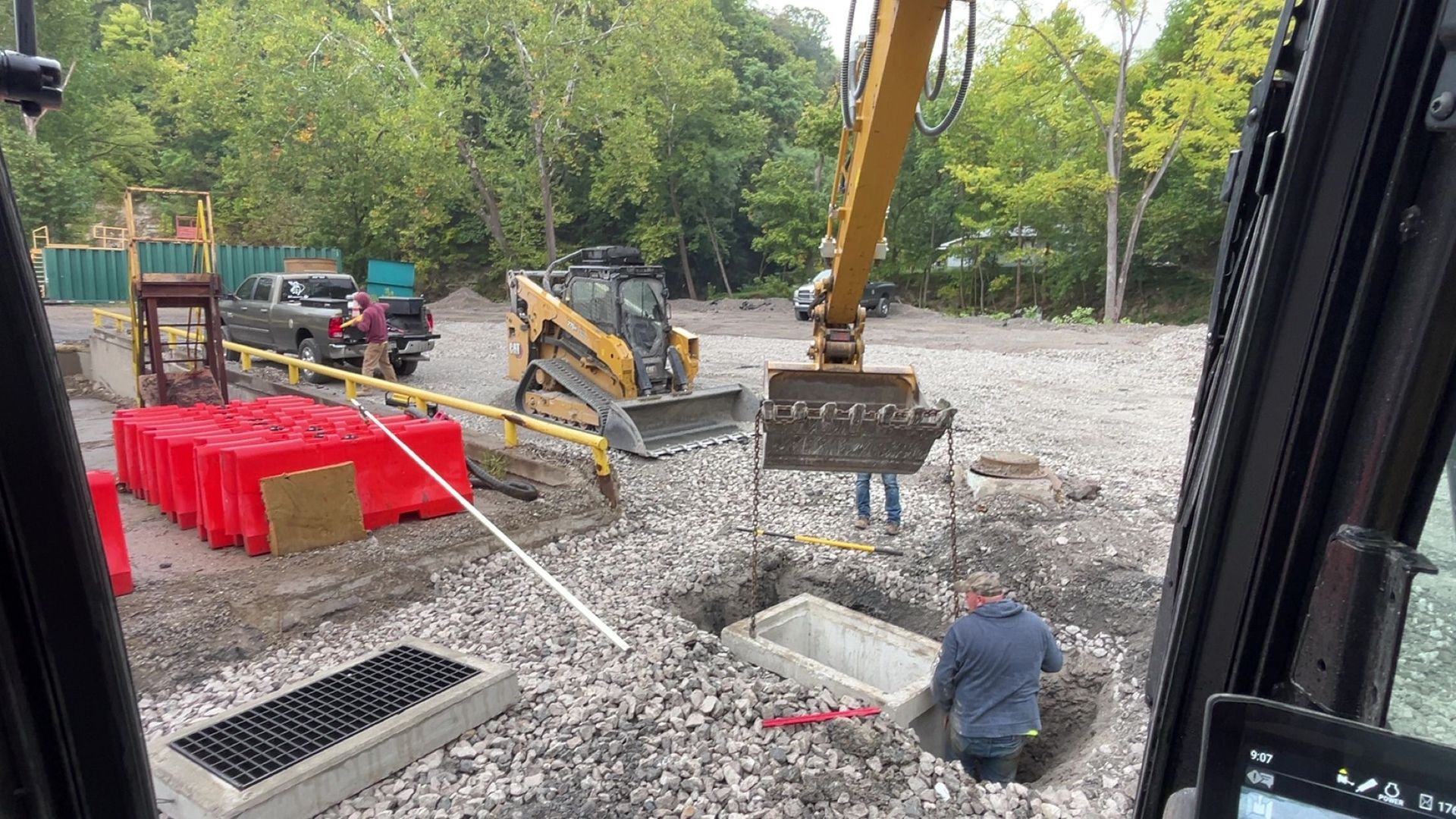 Construction site with excavator, workers, and concrete structures.